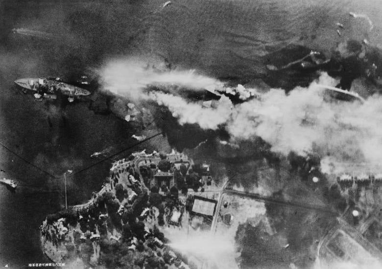 El acorazado USS Arizona arde en Battleship Row, junto a la isla Ford en una foto aérea tomada desde un avión japonés durante el ataque. Los barcos que se ven son (LR) USS Nevada, USS Arizona con USS Vestal fuera de borda amarrado, USS Tennessee con USS West Virginia amarrado fuera de borda y USS Maryland con USS Oklahoma volcado al costado. Comando de Historia y Patrimonio Naval de EE. UU.