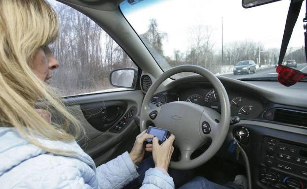 Una mujer sujeta el móvil al volante.