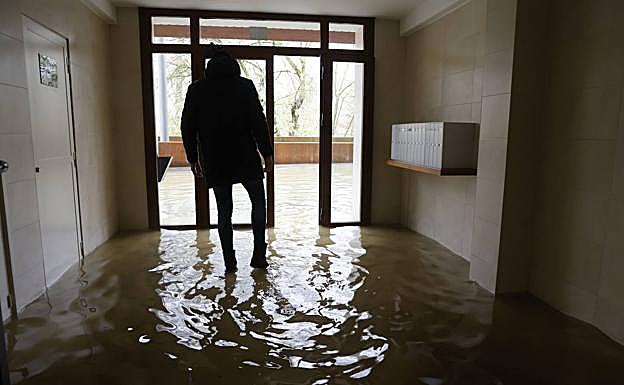 Imagen principal - Un vecino de Abetxuko en uno de los portales inundados. Abajo, la familia de Hamed se ha quedado hoy en casa. Estampa de un patio del barrio colapsado por la ríada. 