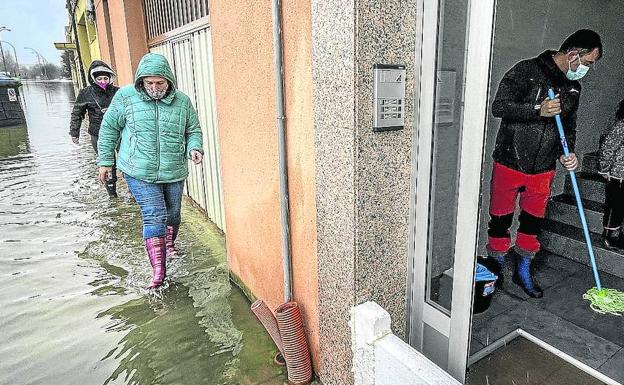 Imagen principal - Botas de goma y fregona para secar el agua que llegó a los portales en Asteguieta y Abetxuko. En ambos barrios el nivel alcanzó entre 30 y 50 centímetros en la calle. R. Gutiérrez / J. Andrade 