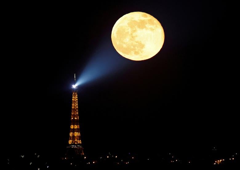 La luna llena, conocida como la "Super Luna Rosa", se eleva detrás de la Torre Eiffel en París, Francia, el 27 de abril de 2021.