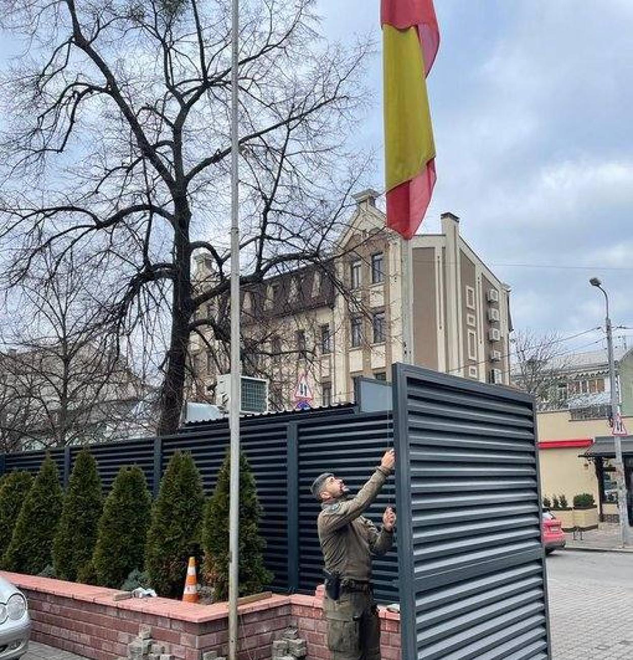 Un funcionario retira la bandera española de la embajada en Kiev. 