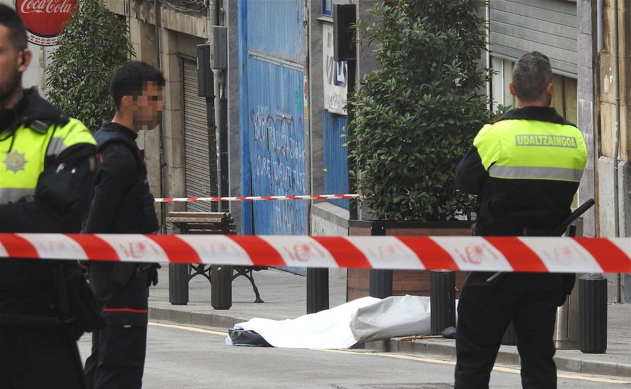 El cadáver de la víctima yace en el suelo custodiado por los agentes. 