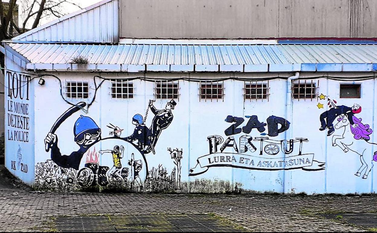 Mural en el que se ve a un ertzaina empalado y el mensaje en francés de odio a la policía, en el lateral. 