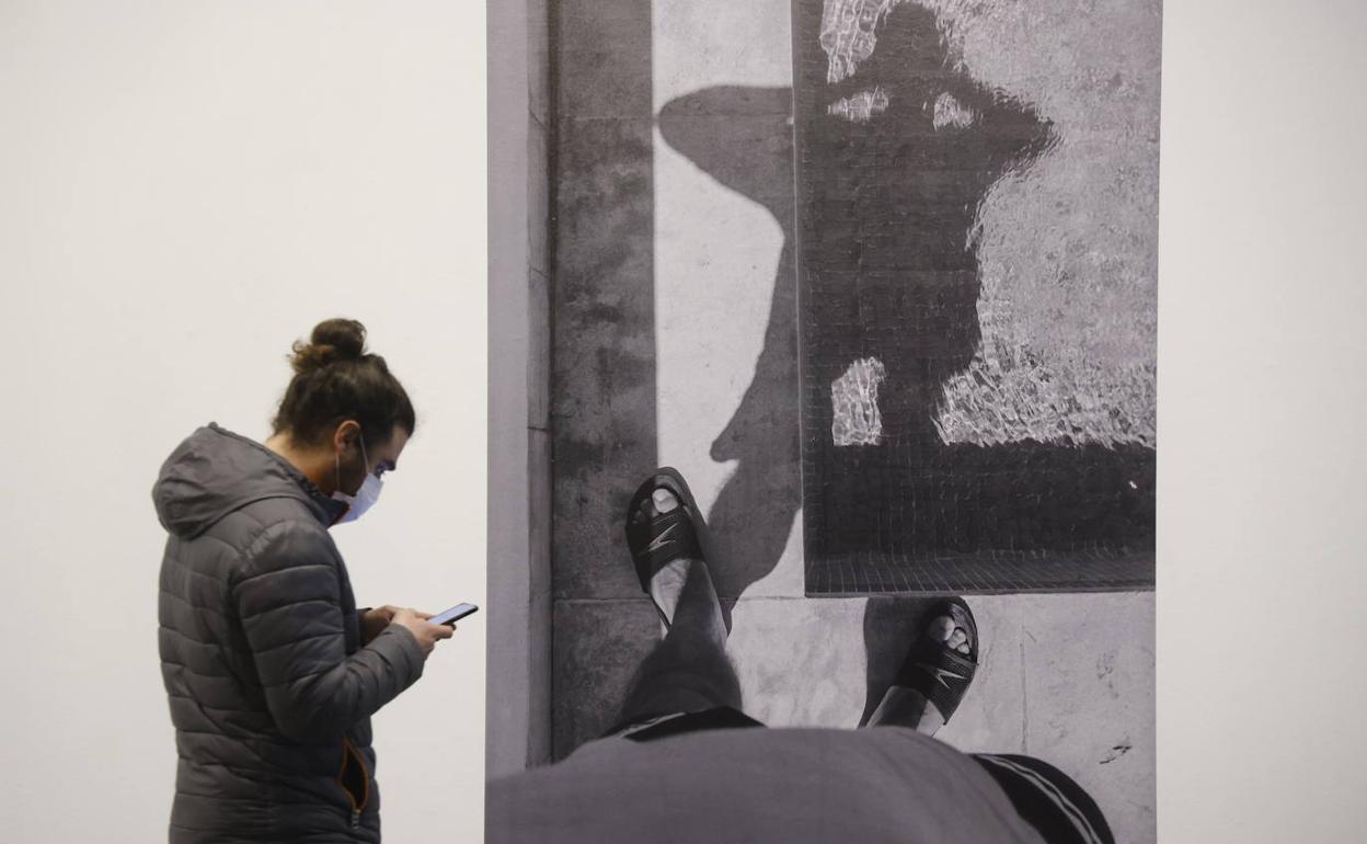 Un visitante en la Sala Amárica junto a la fotografía que se puede ver al entrar a la derecha. 