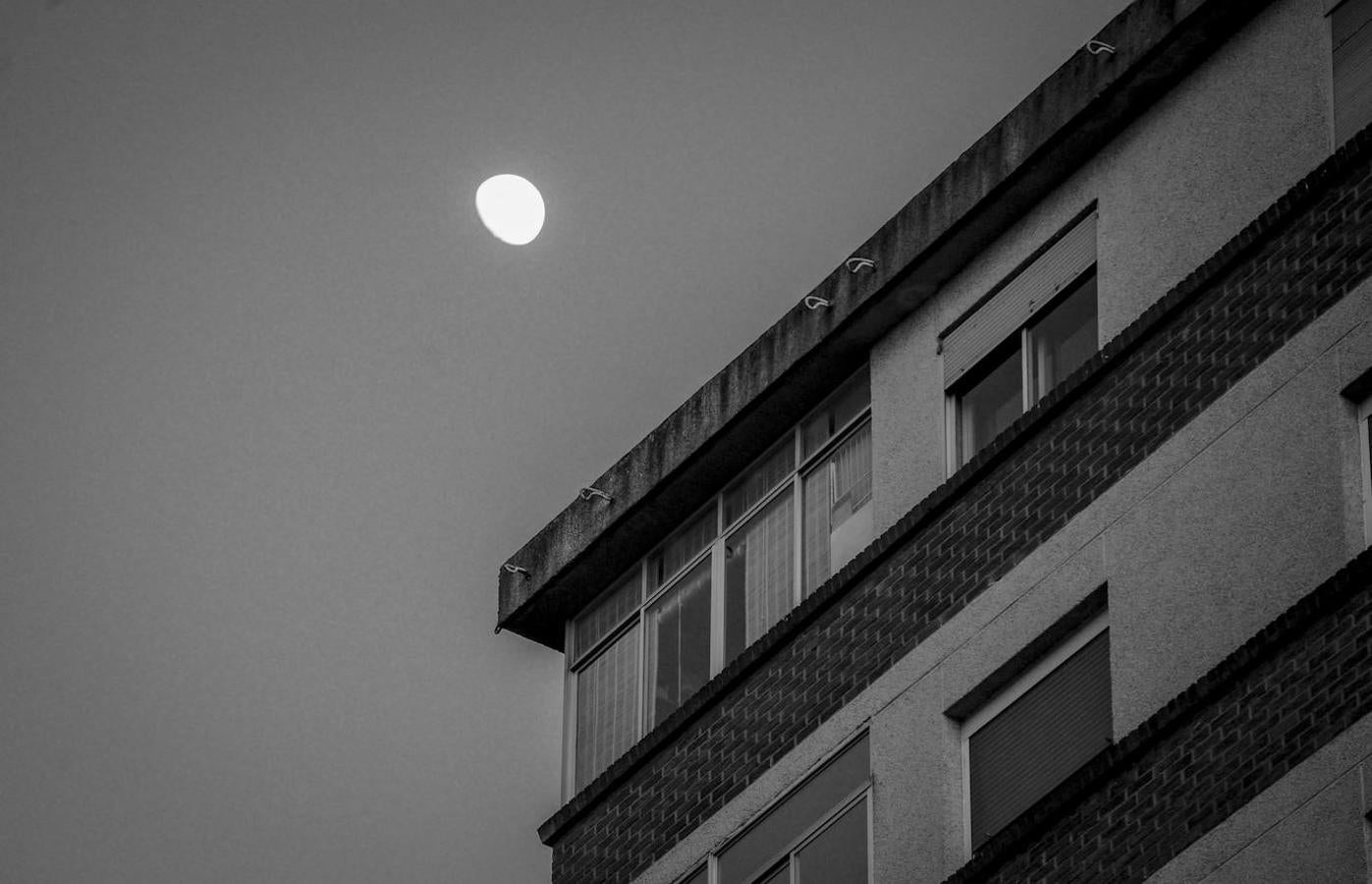 La luna, en cuarto menguante sobre un bloque de viviendas.