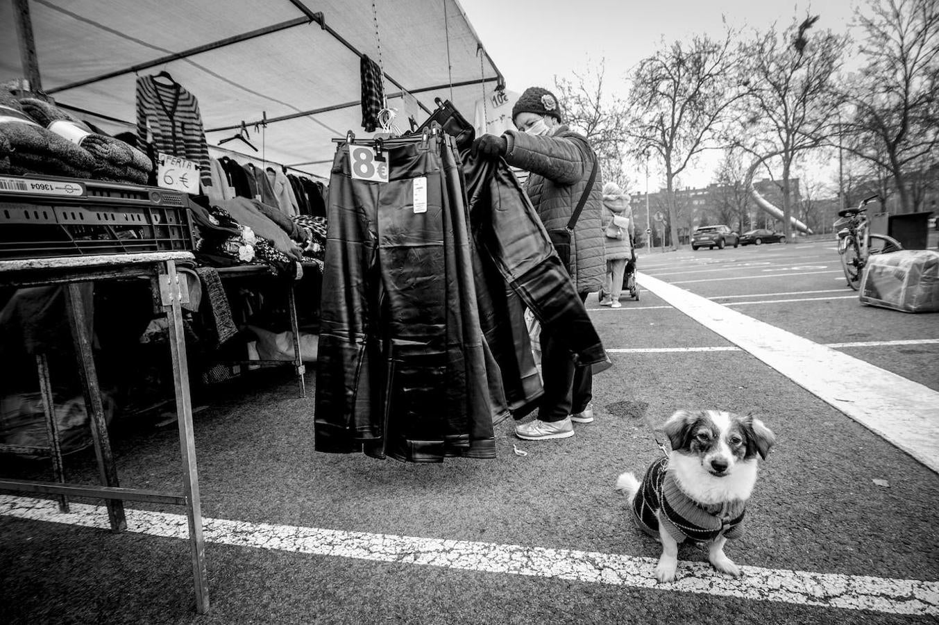 Una clienta echa un vistazo a los pantalones colgados en uno de los puestos del mercado que se levanta en Portal de Foronda. Al fondo se asoma la escultura 'La inocencia, lo inesperado' de Imanol Marrodán que hasta 2011 estaba en la plaza de Euskaltzaindia.