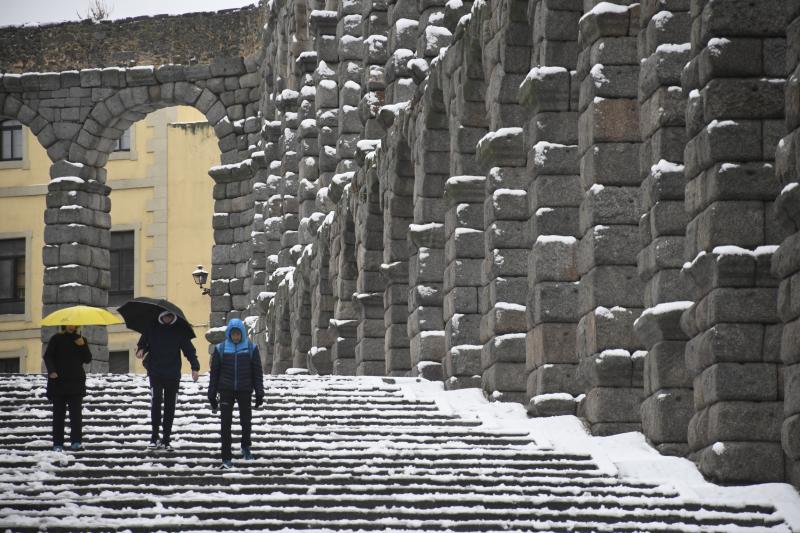 Varias personas caminan junto al acueducto de Segovia que este miércoles ha amanecido cubierto de nieve. 