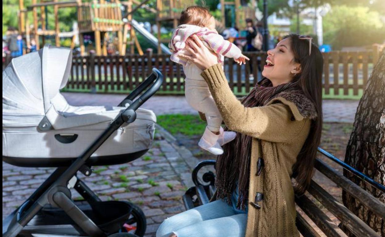 Una madre juega con su hija recién nacida en un parque. 