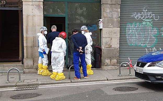 Agentes de la Policía Científica, con buzos, acceden ayer al interior de la lonja incendiada hace un mes en Atxuri. 