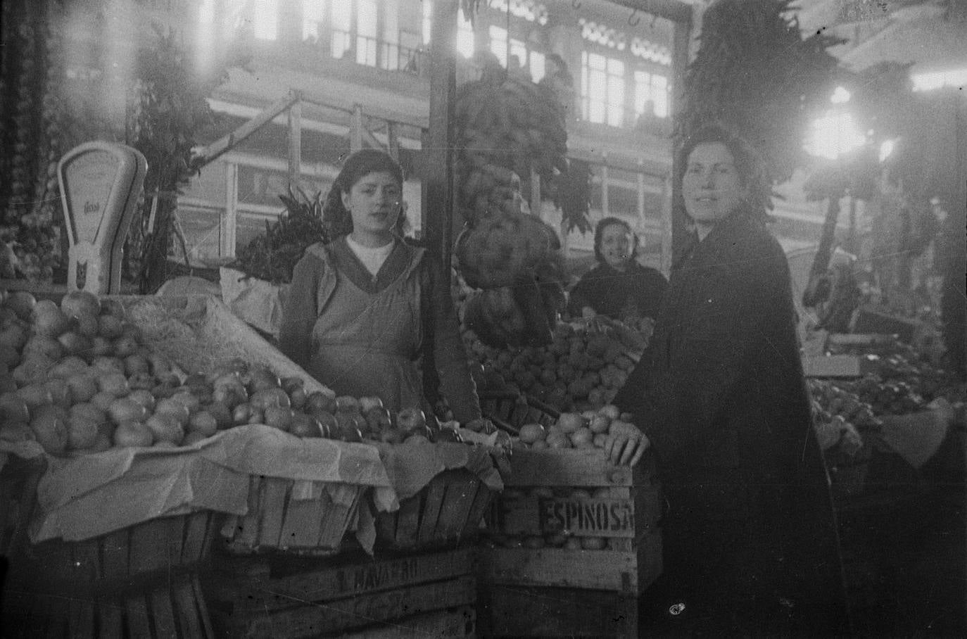 Retratos de dos mujeres en un puesto de frutería en el interior de la antigua plaza de abastos de Vitoria