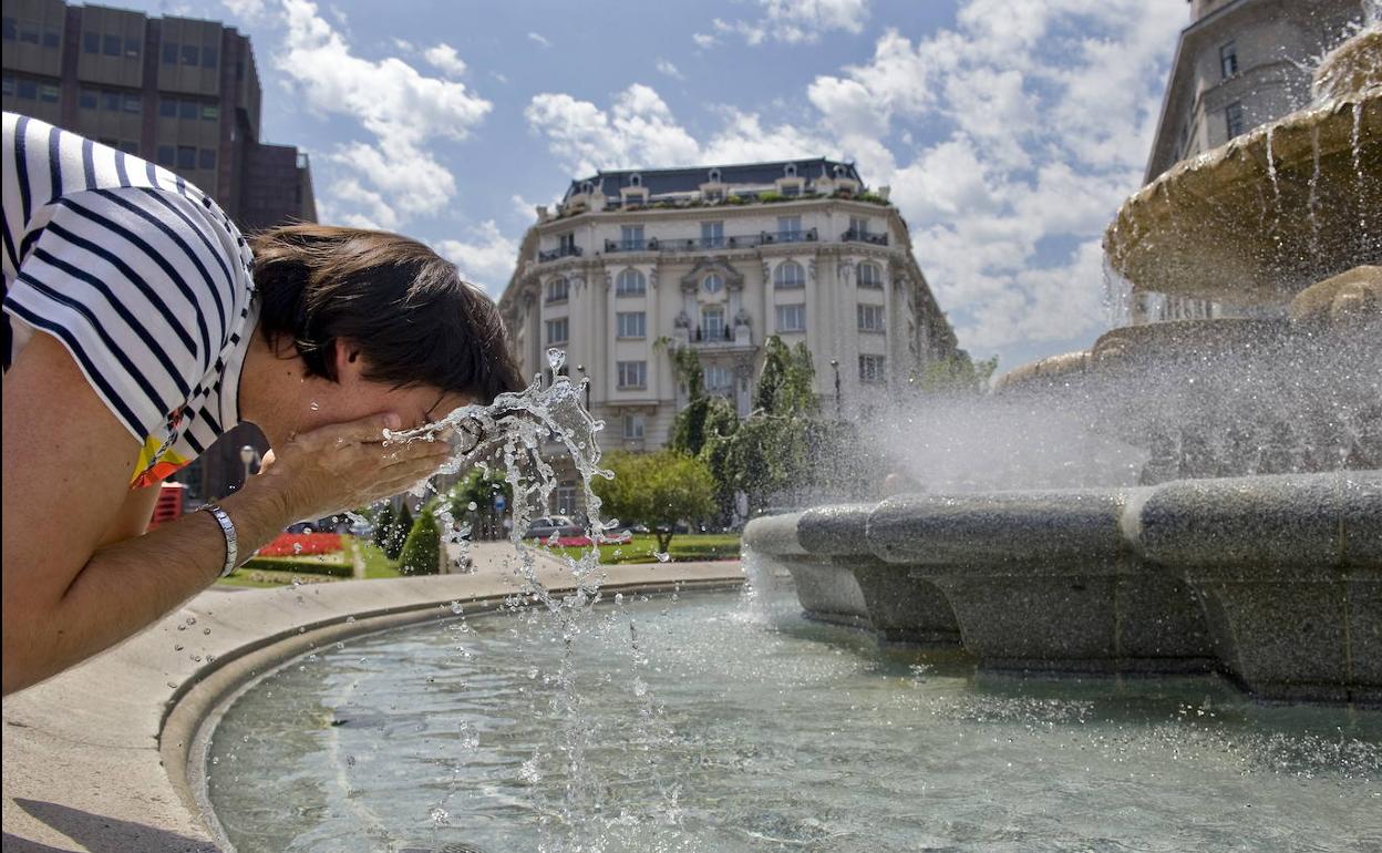 Una mujer se refreca en la fuente de la Plaza Moyua.