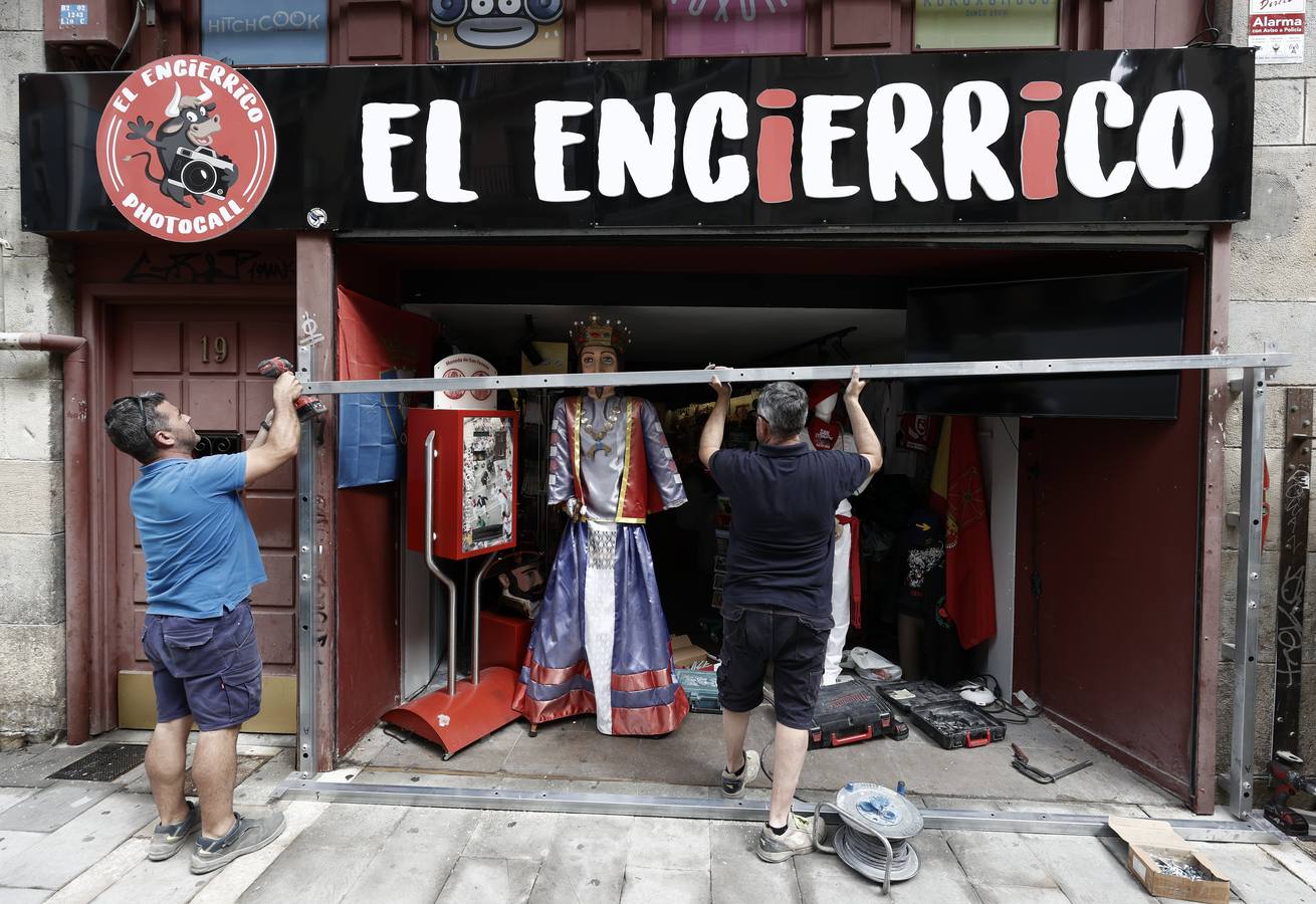 La dueña de un comercio del Casco Viejo de Pamplona coloca para su venta la ropa típica de los Sanfermines en la entrada a la tienda. 