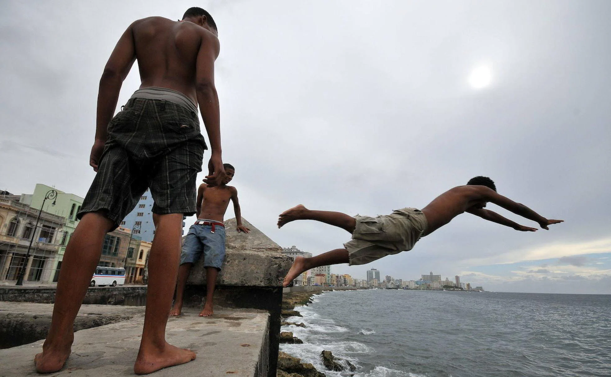 Jóvenes se lanzan al agua en el Malecón de La Habana. 