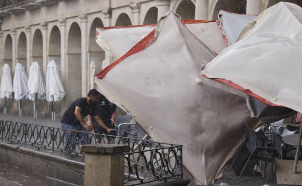 El fuerte viento que ha traído la tormenta se ha llevado por delante el mobiliario de las terrazas como esta de la plaza de España. 