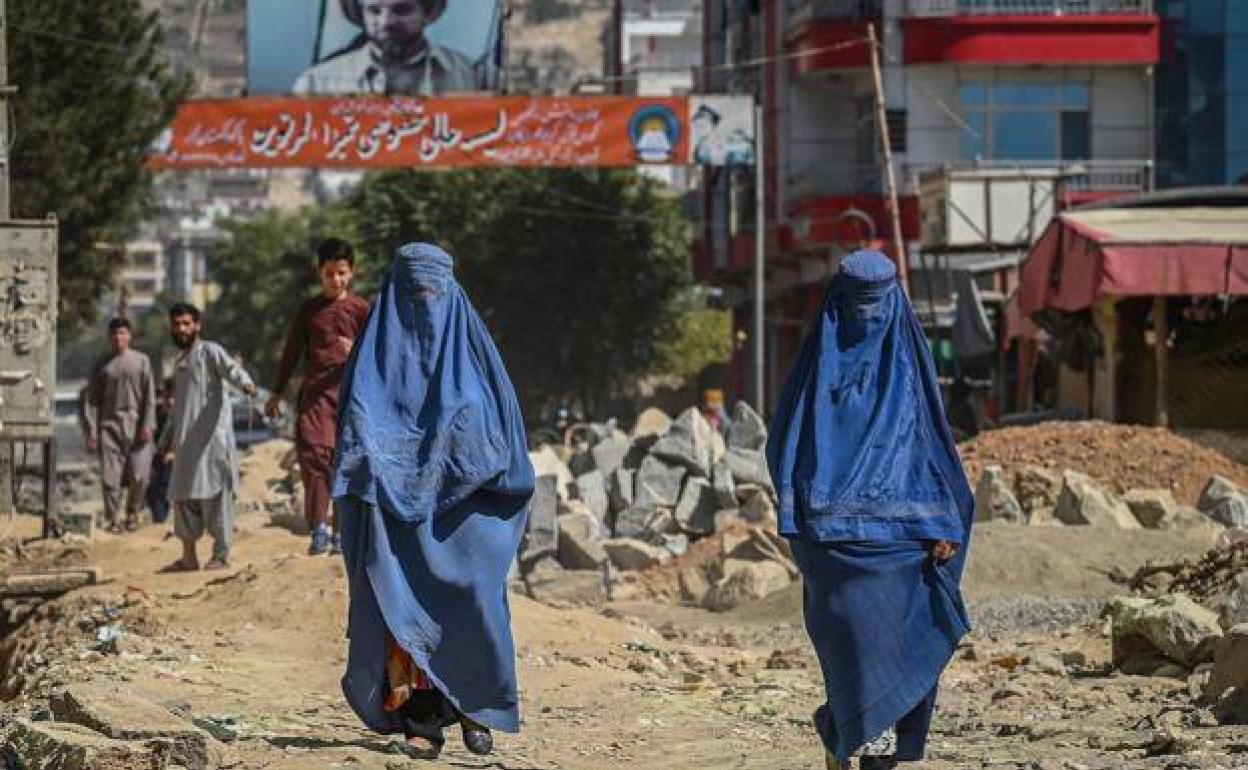 Dos mujeres caminan por la calle, ante la mirada de los hombres, en Kabul. 