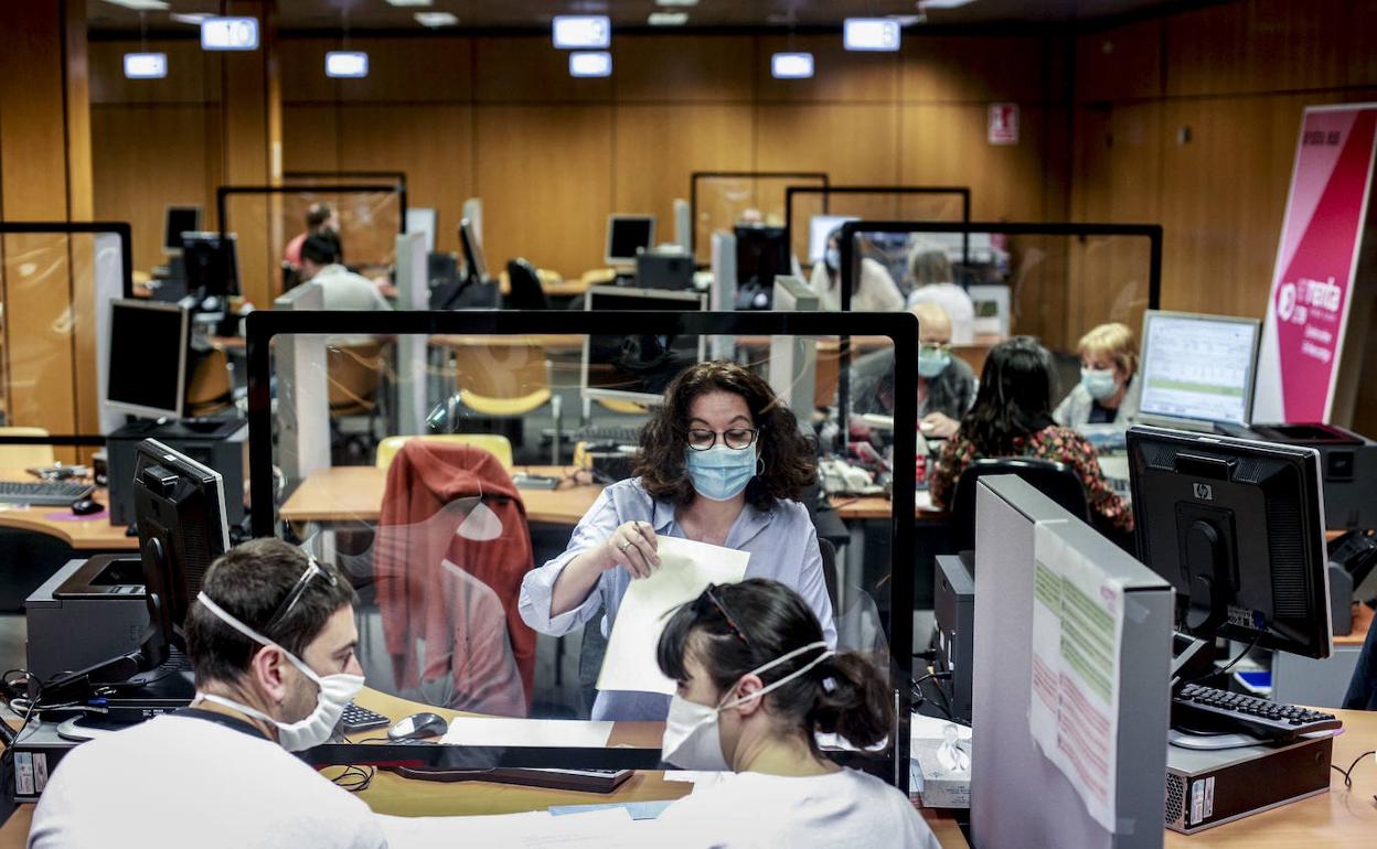 Una trabajadora de la Hacienda foral alavesa atiende a dos jóvenes en las instalaciones de Vitoria.