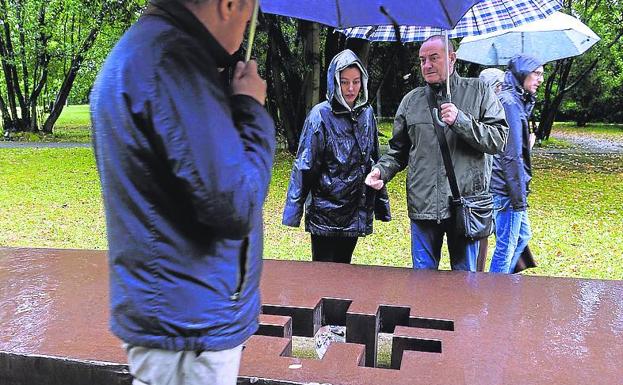 Protegidos bajo la lluvia, junto a una de las esculturas del parque.