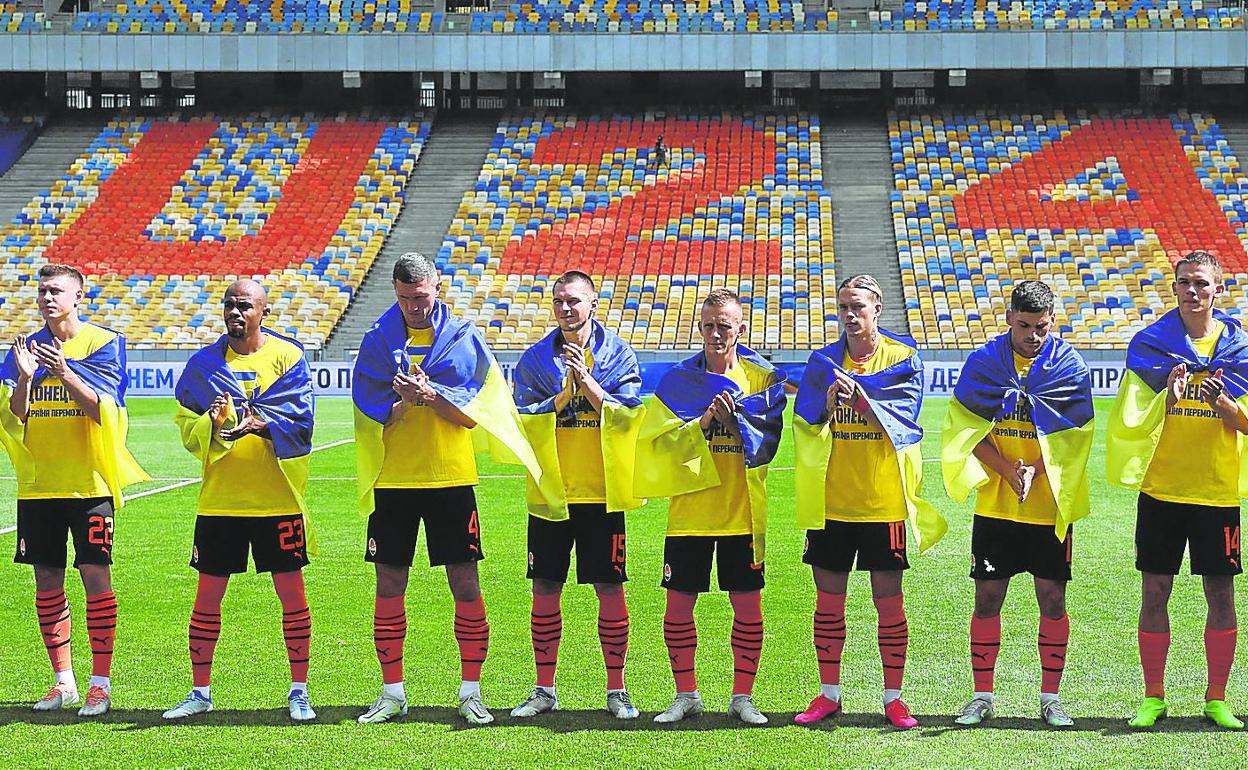 El primer partido. Los jugadores del Shakhtar, envueltos en banderas ucranianas, escuchan las alineaciones antes de medirse al Metalist. 