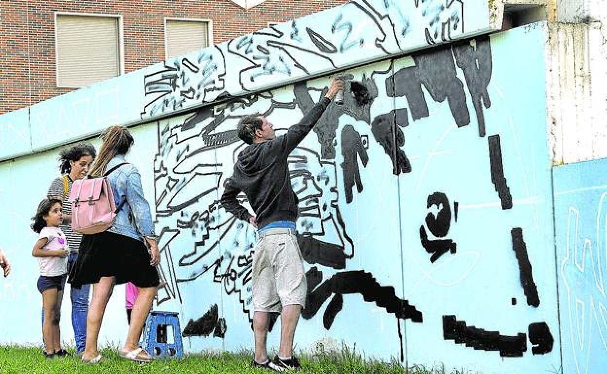 Una treintena de vecinos de Goikolarra pinta un mural para tapar grafitis y crear un entorno amigable.