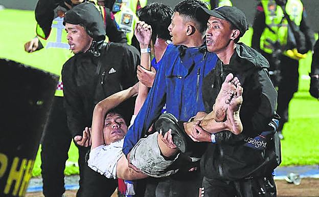 Un grupo de hinchas ayudan a otro herido.