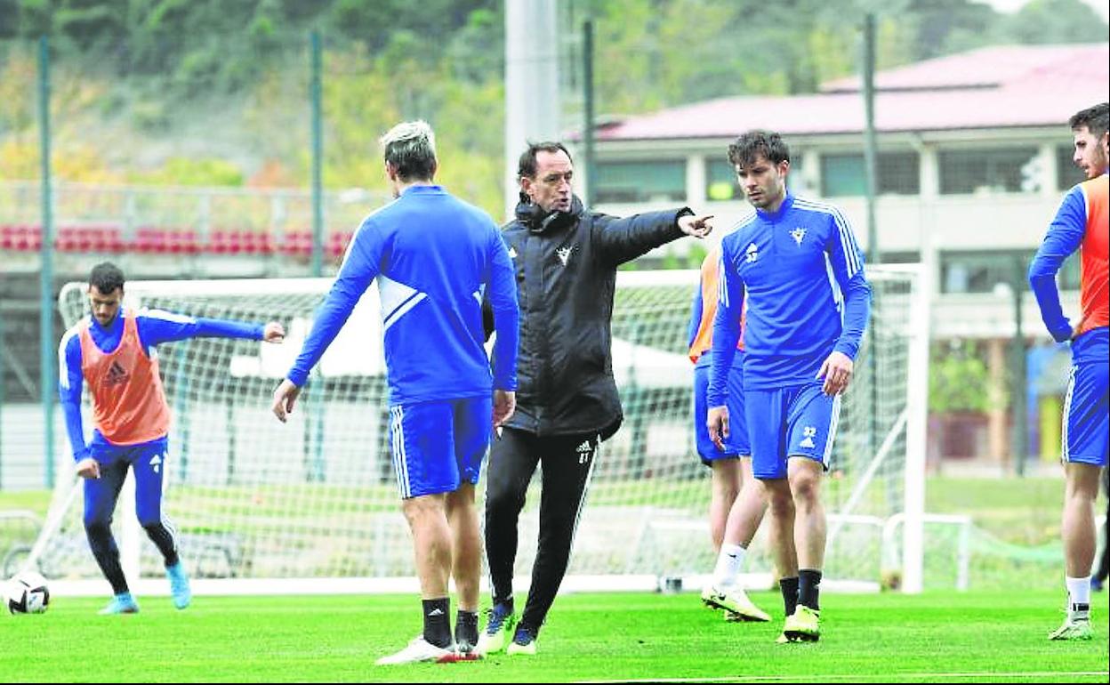 Joseba Etxeberria, junto a Nacho Castillo, jugador del Mirandés B que viajó ayer a Oviedo, distribuye a los futbolistas antes de un ejercicio. 