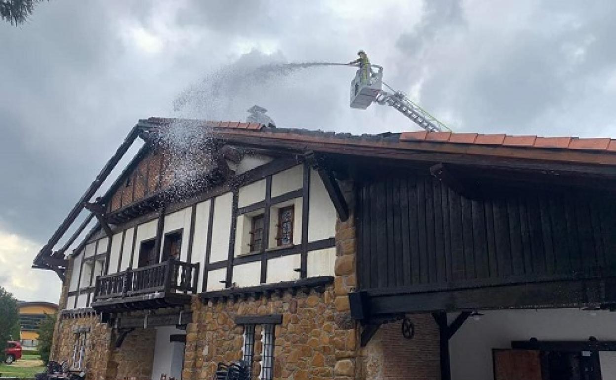 Los bomberos apagan el incendio que destrozó el tejado del caserío. 