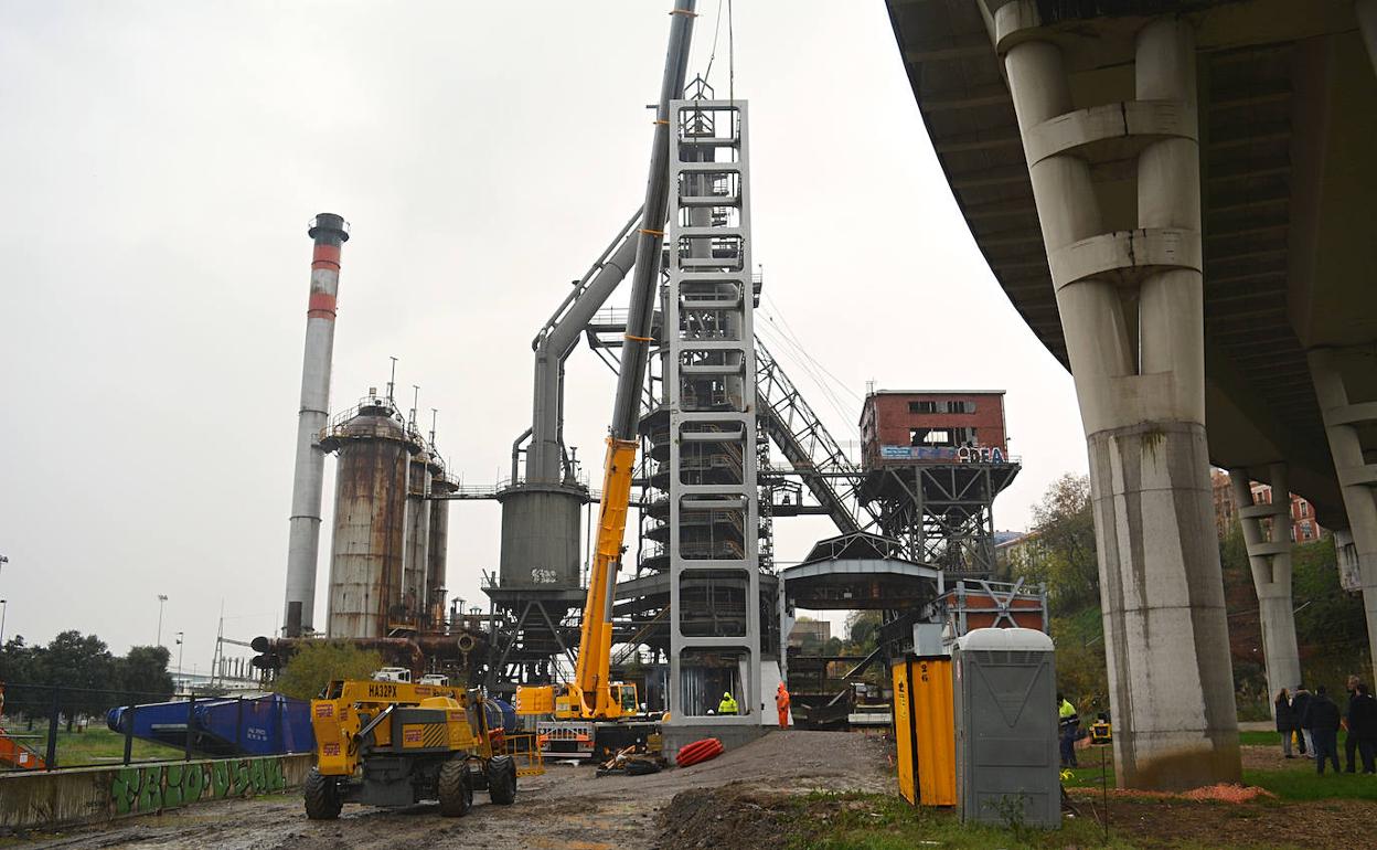 Operarios y una grúa trabajando en el lugar, tras el izado de la estructura en la que irá colocado el ascensor, para salvar los 26 metros que hay hasta el vial que da acceso a La Benedicta. 