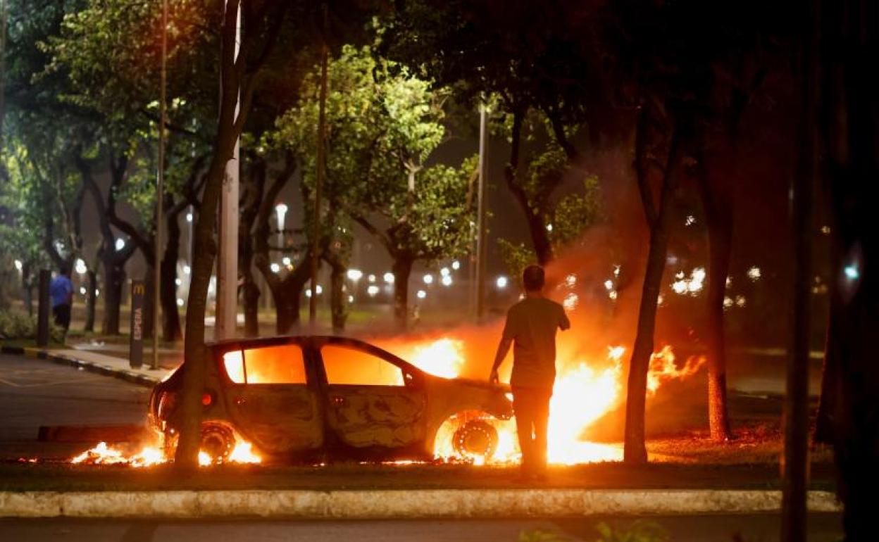 Un individuo observa un vehículo en llamas en Brasilia. 