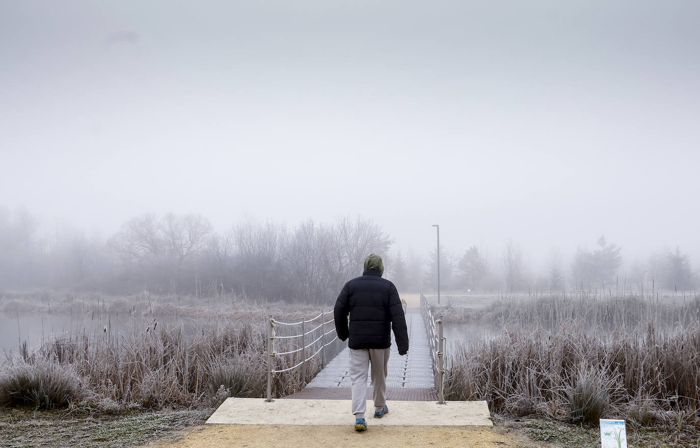 Un hombre cruza el puente sobre el lago de Olarizu.