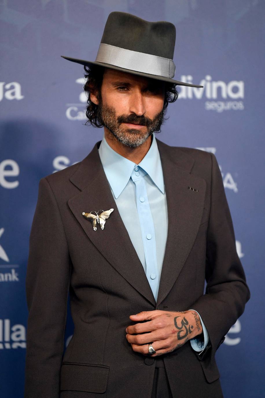 El músico madrileño Leiva vuelve a ser fiel a su estilo con sombrero de Nick Fouquet y traje, camisa, broche y zapatos de Gucci.