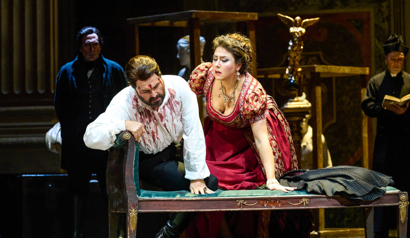 La soprano ucraniana Oksana Dyka (Tosca), inclinada junto al tenor Roberto Anorica (Mario Cavaradossi), que acaba de ser torturado por los esbirros del barón Scarpia. 