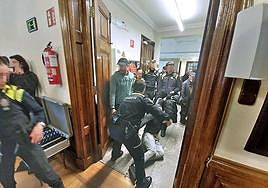 Los agentes sacan al exterior a un joven que se negaba a levantarse de la sala.