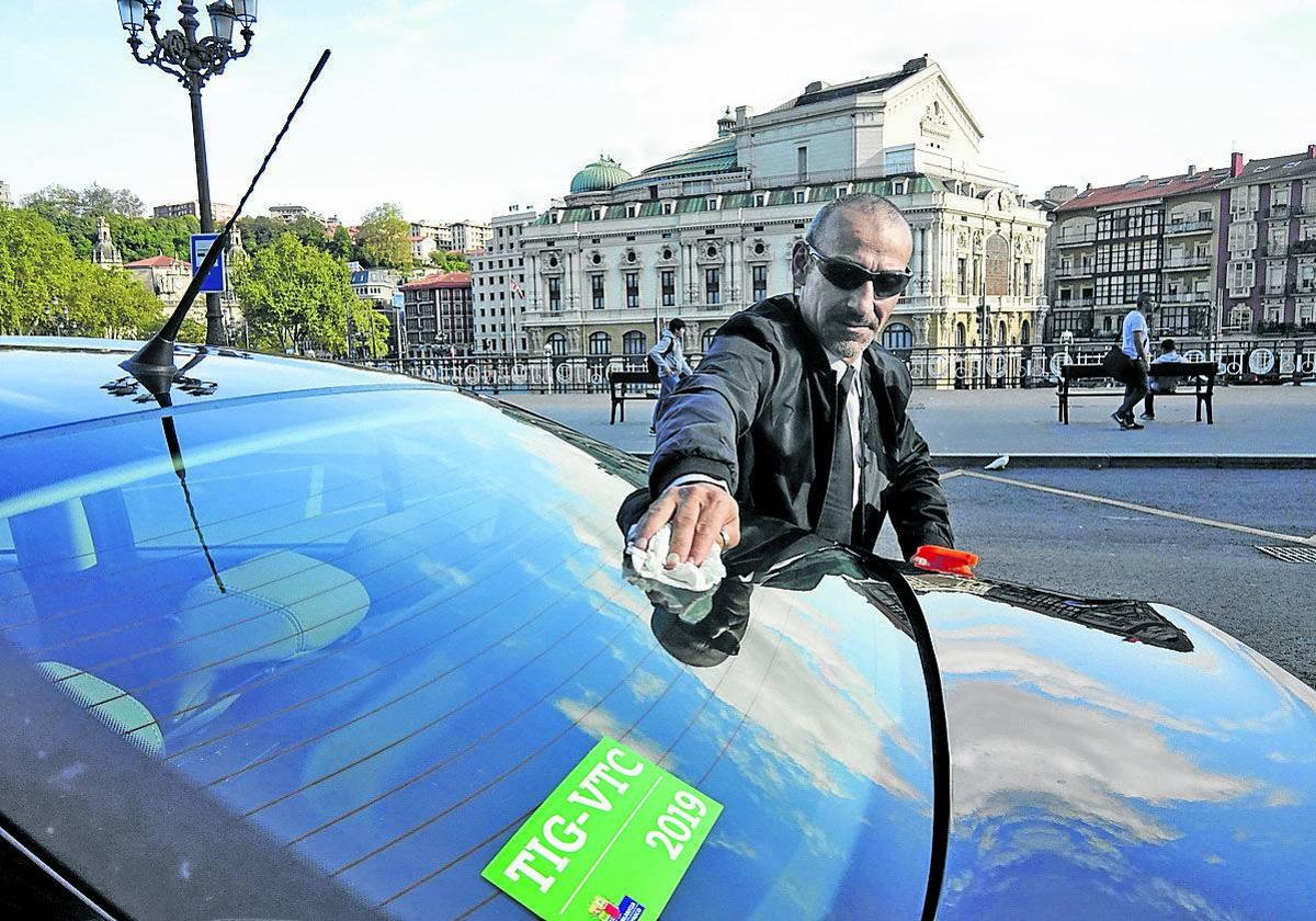 Un conductor de un VTC limpia su vehículo en Bilbao.