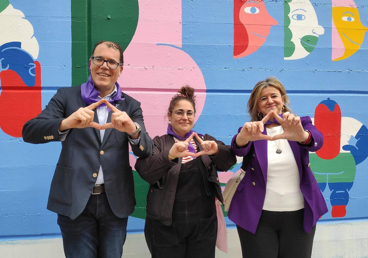 El alcalde de Ortuella, Saulo Nebreda, la autora del mural, Janire Orduna, y la diputada Teresa Laespada hacen el gesto feminista con las dedos formando un triángulo.