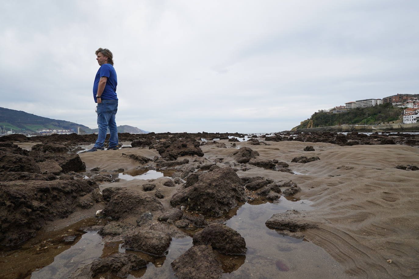 Un hombre camina sobre rocas en la playa de Ereaga. MANU CECILIO