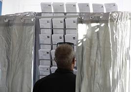 Un hombre observa las papeletas en una cabina electoral.