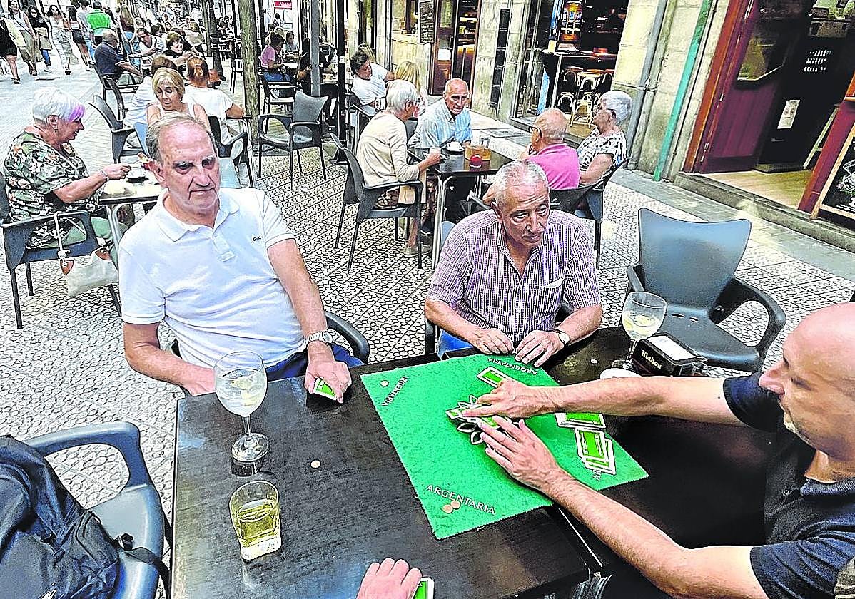 Jubilados juegan a cartas en la terraza de un bar en Bilbao.