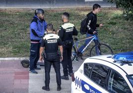 Dos agentes aperciben a un joven en patín por la acera.