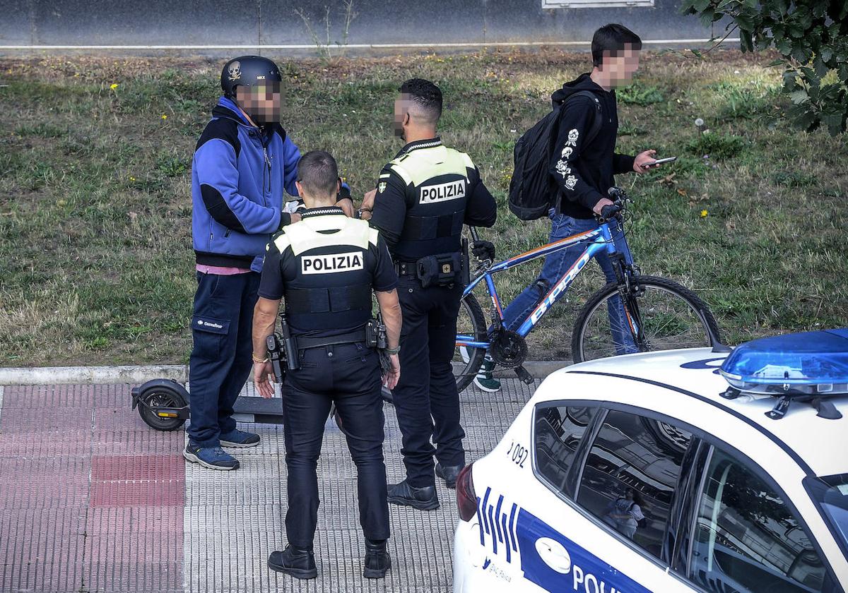 Dos agentes aperciben a un joven en patín por la acera.