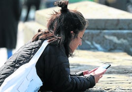 Una joven consulta su teléfono móvil.