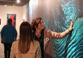 Una mujer con baja visión toca el ojo de la imagen a tamaño natural de la ballena que forma parte de la muestra.