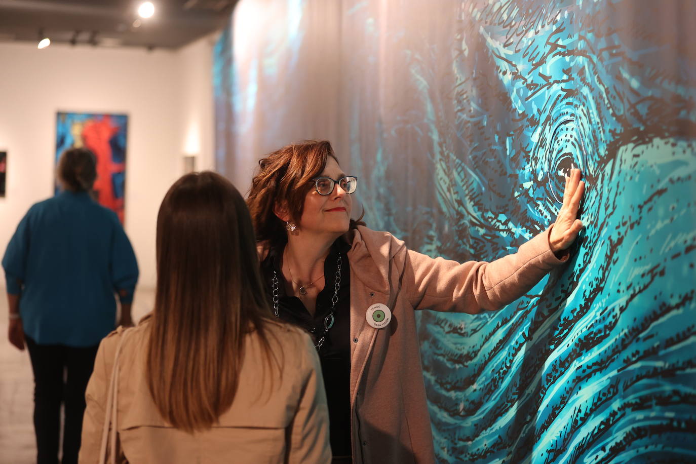 Una mujer con baja visión toca el ojo de la imagen a tamaño natural de la ballena que forma parte de la muestra.