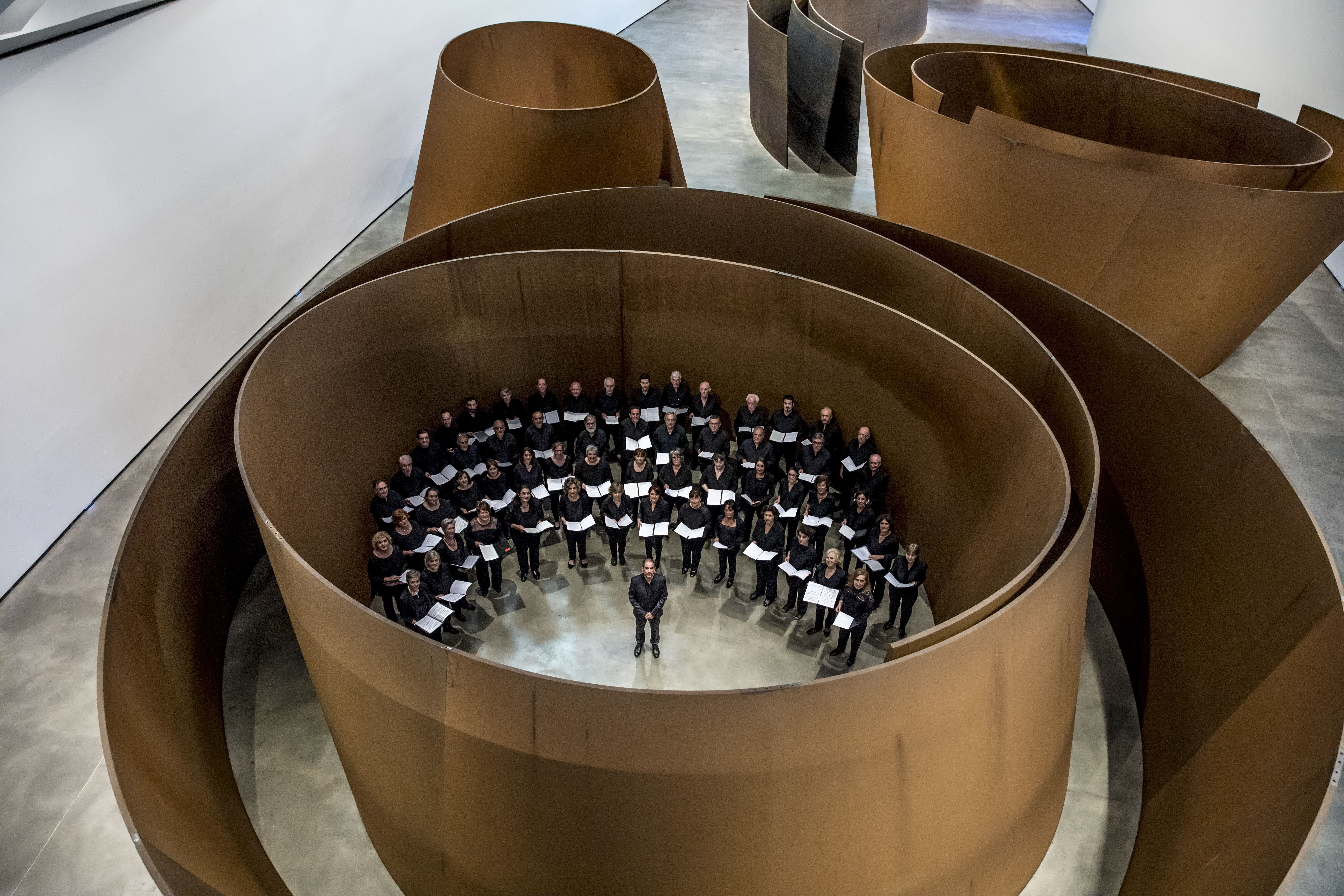 La Sociedad Coral, con Enrique Azurza al frente, posando en el marco de 'La materia del tiempo', de Richard Serra.