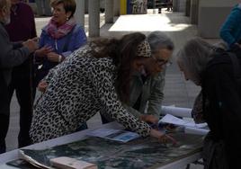 Tres mujeres consultan el póster en Areta.