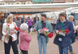 Ander Larrinaga hace entrega de una rosa a una vecina en el mercado de los lunes de Gernika.