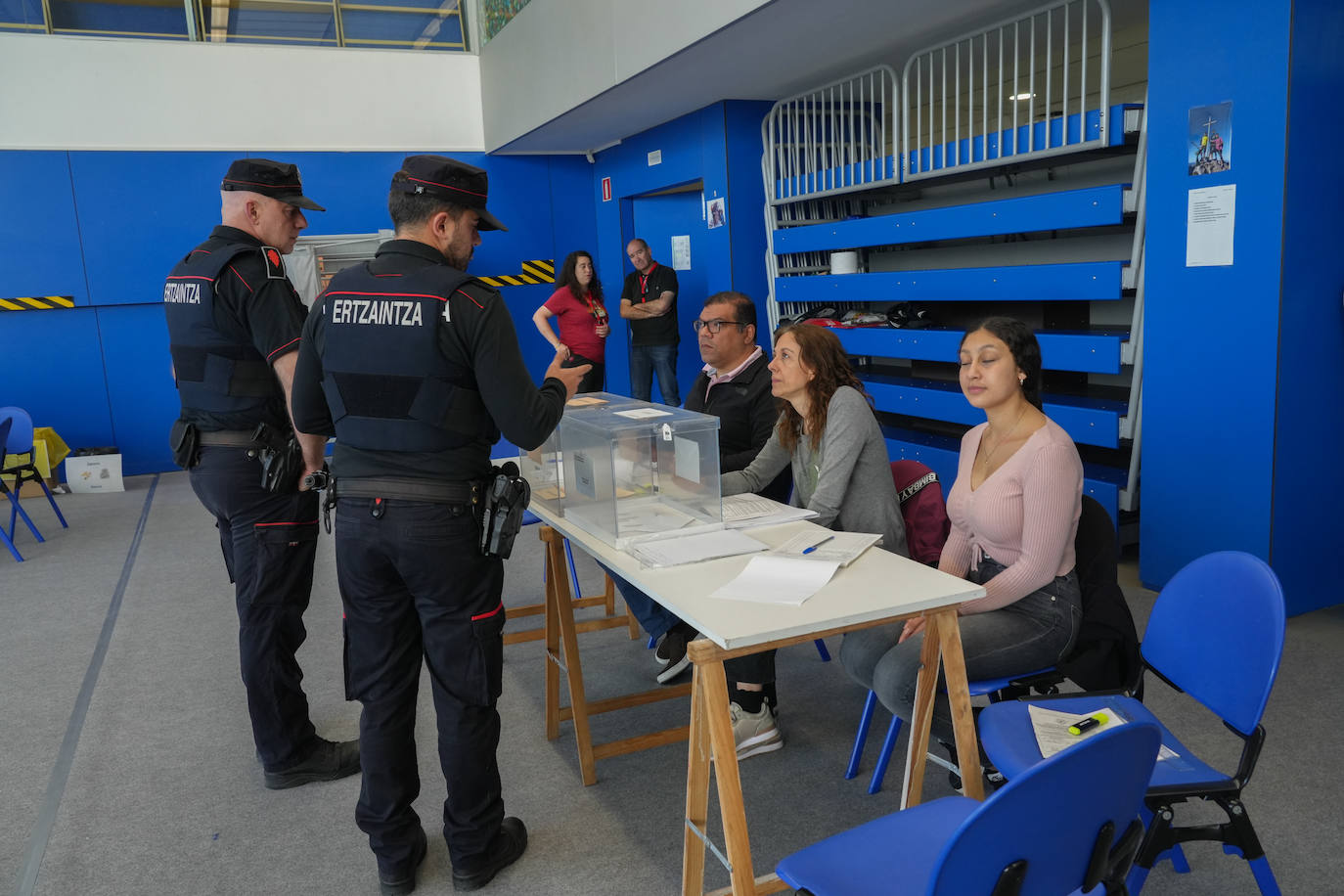 Un par de ertzainas pasan por una mesa electoral del barrio vitoriano de Salburua.