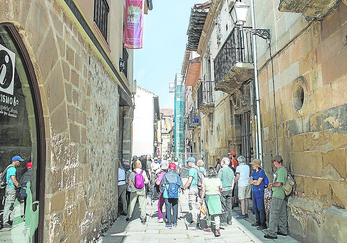 Visitantes junto a la oficina de turismo y el edificio recientemente declarado en ruina, en la calle Mayor.