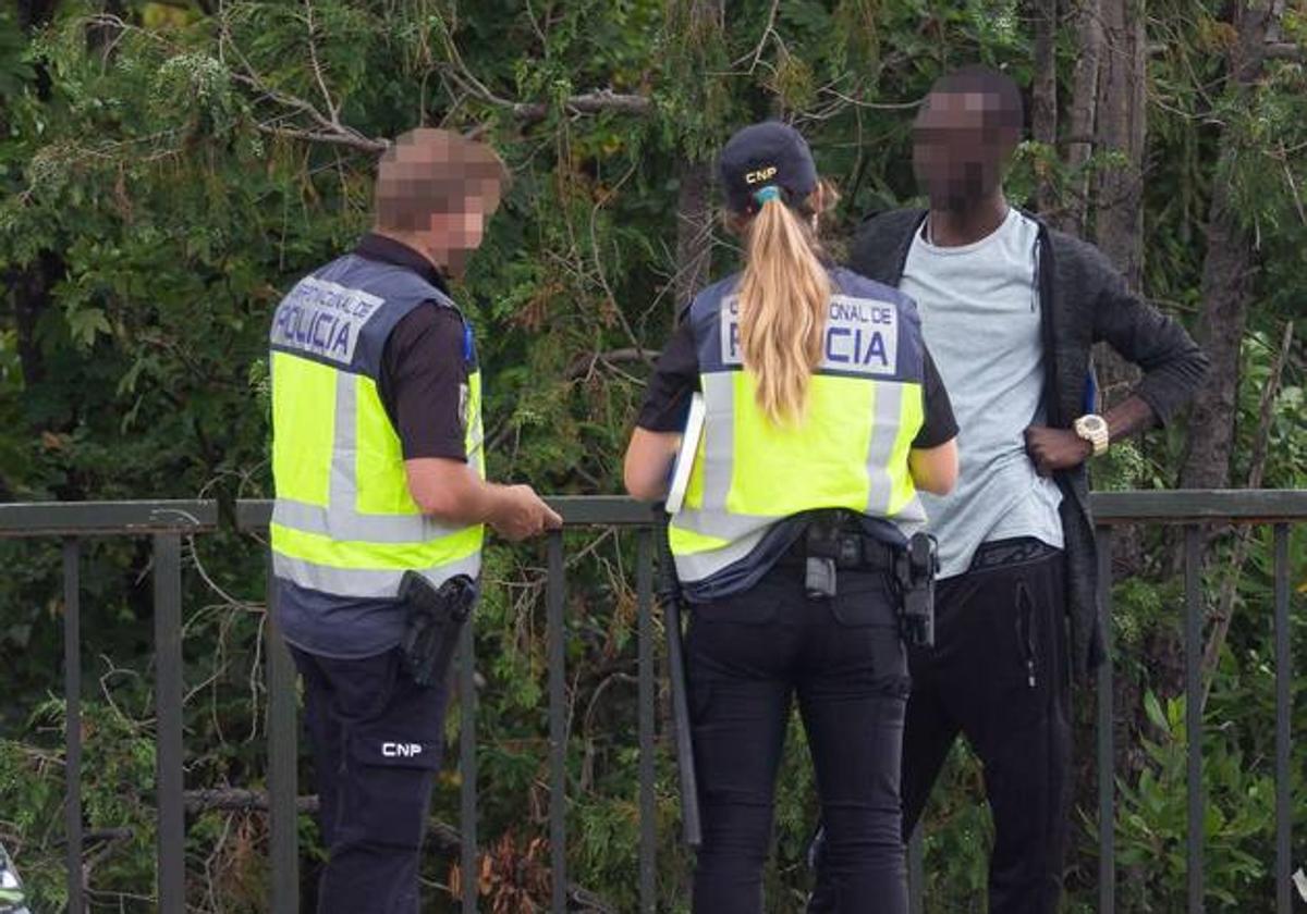 Dos agentes identifican a un inmigrante en la muga.