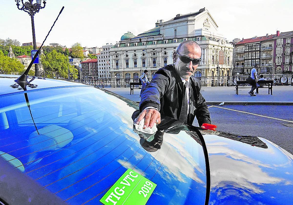 Un conductor de Uber limpia la luna trasera de su vehículo frente al teatro Arriaga.